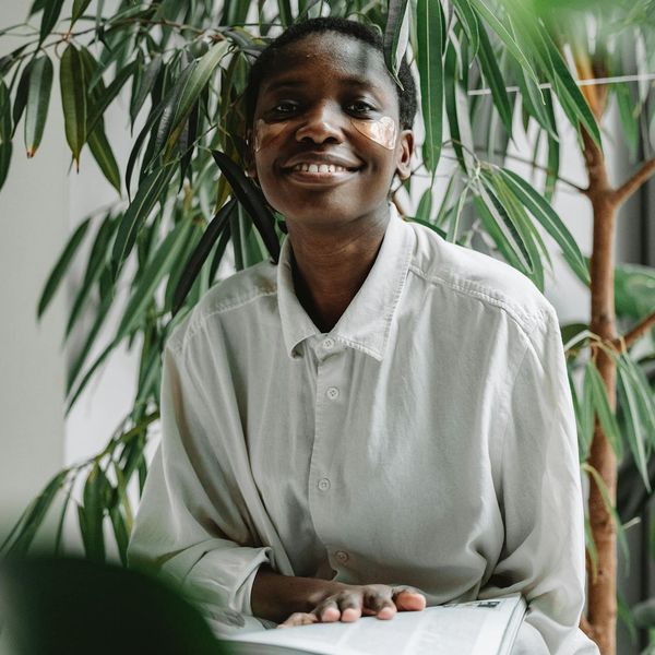 Person smiling peacefully in a bright, natural setting.